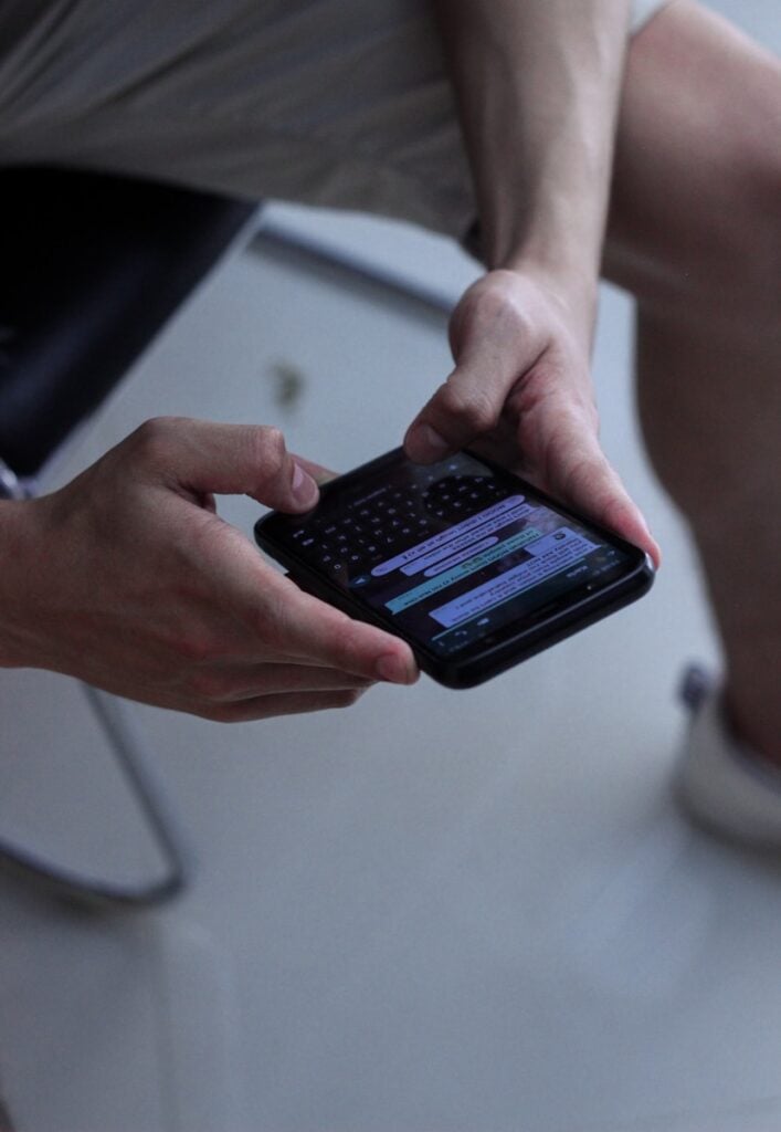 person holding black iphone 4 with chat app up