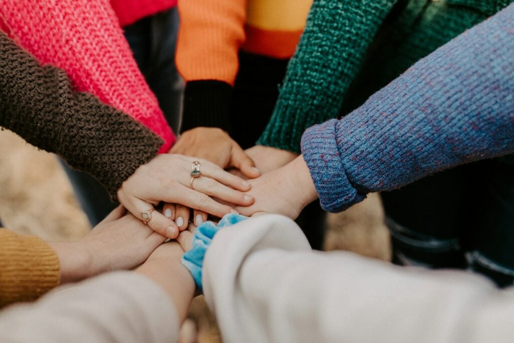 a bunch of people with their hands in a stack as a team